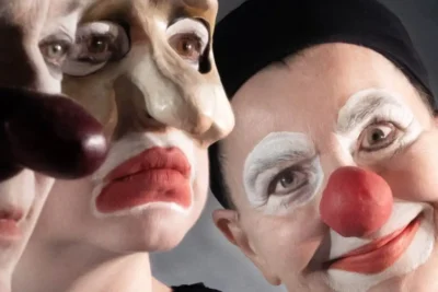 Närbild av tre clowner med vit smink kring ögonen och röda munnar.