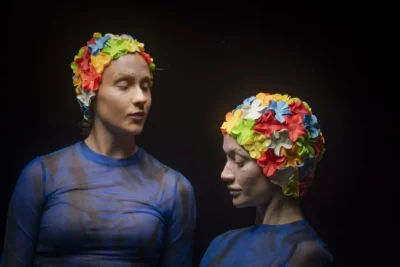 Två personer i mörkt rum med färgglada mössor.