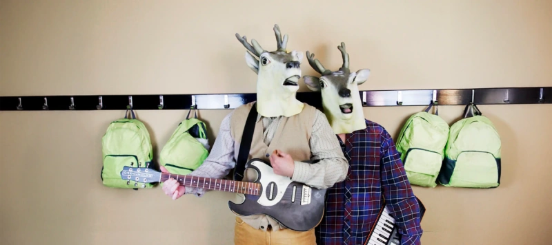 Två personer utanför ett klassrum med plastmasker som liknar ett rådjur.