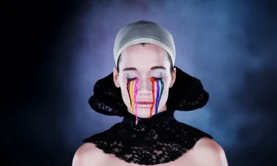 Kvinna med stängda ögon, olika färger som rinner nerför kinden likt tårar.