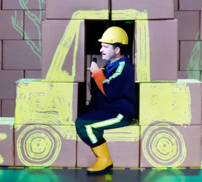 Man i gul hjälm som sitter i bil skapad av kartong.